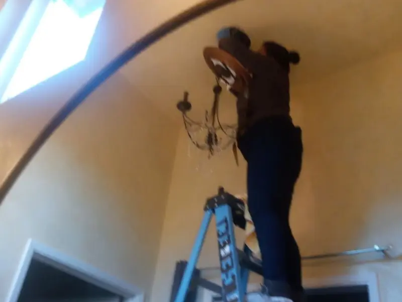 Electrician installing a chandelier in a Lakeview residence